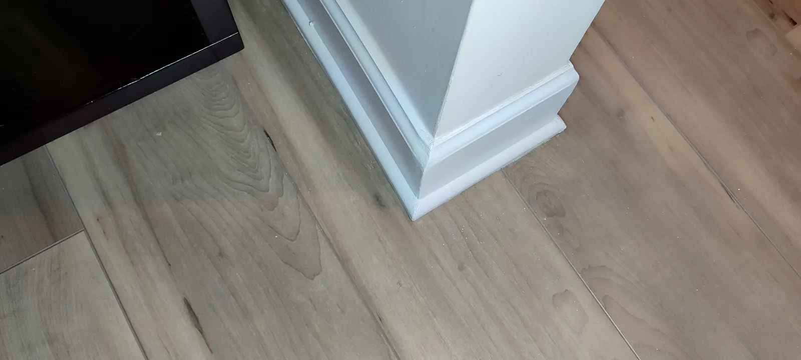 Finished baseboard corner beside the dark cabinet