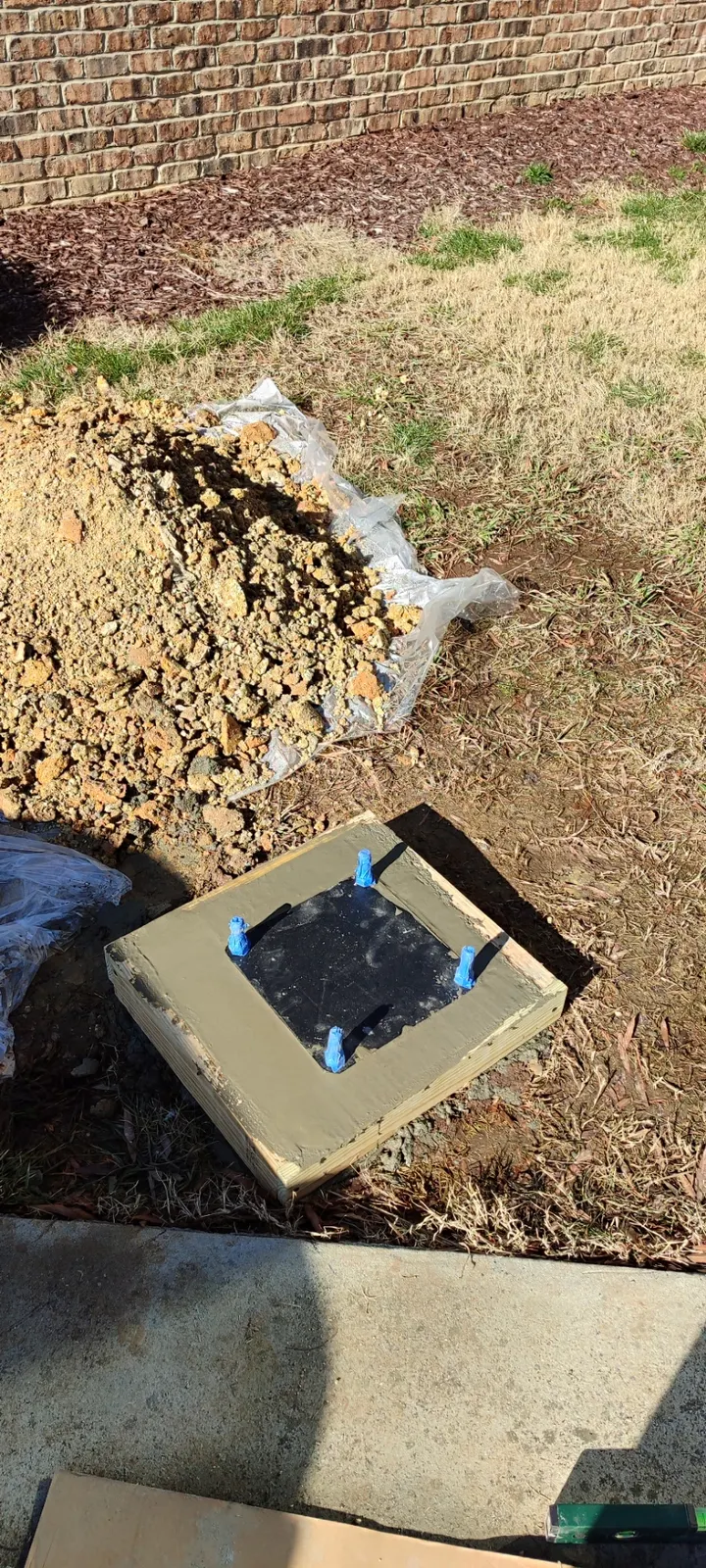 Concrete base and anchor plate inside the wooden form