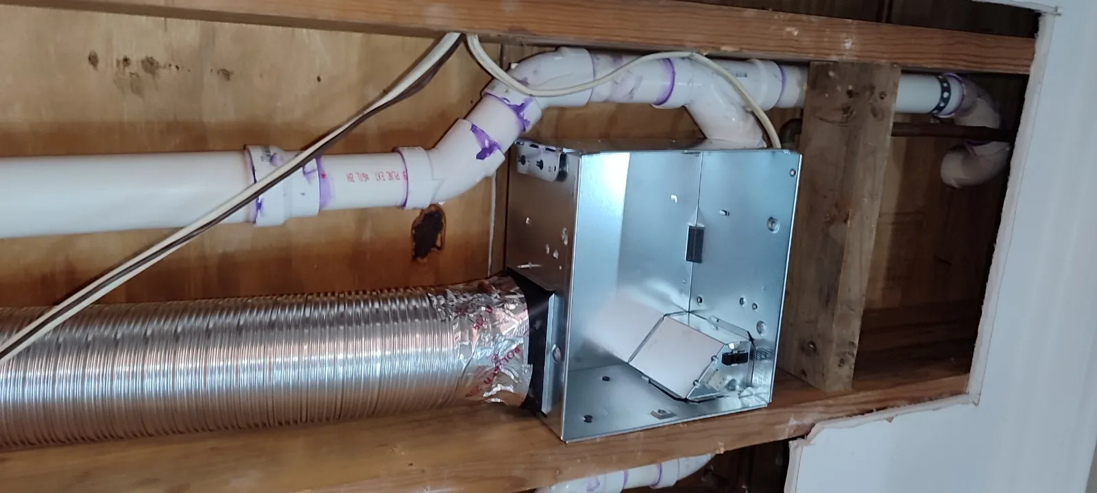 Bathroom exhaust fan housing installed in the open ceiling cavity and connected to the ventilation duct