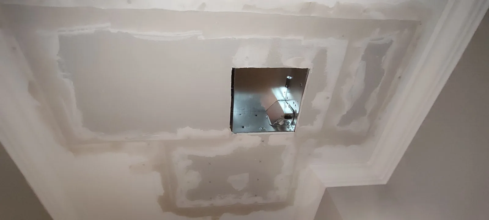 Repaired bathroom ceiling prepared for final sanding and painting around the fan opening