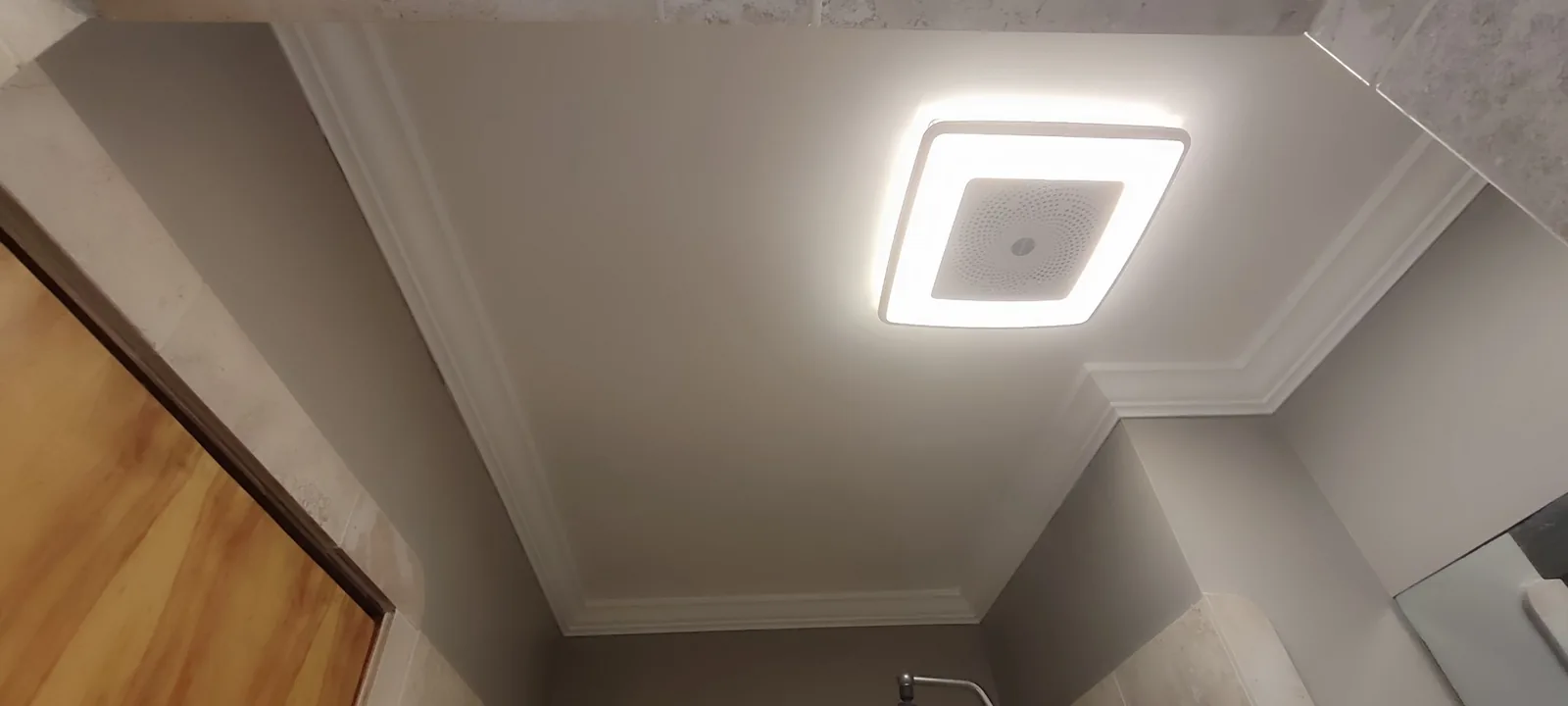Finished bathroom ceiling showing the installed exhaust fan light and completed surrounding drywall