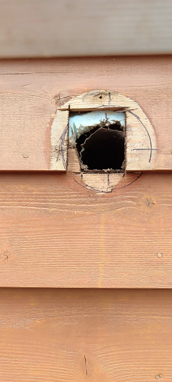Existing bathroom exhaust duct opening in exterior siding before installing the new vent cover