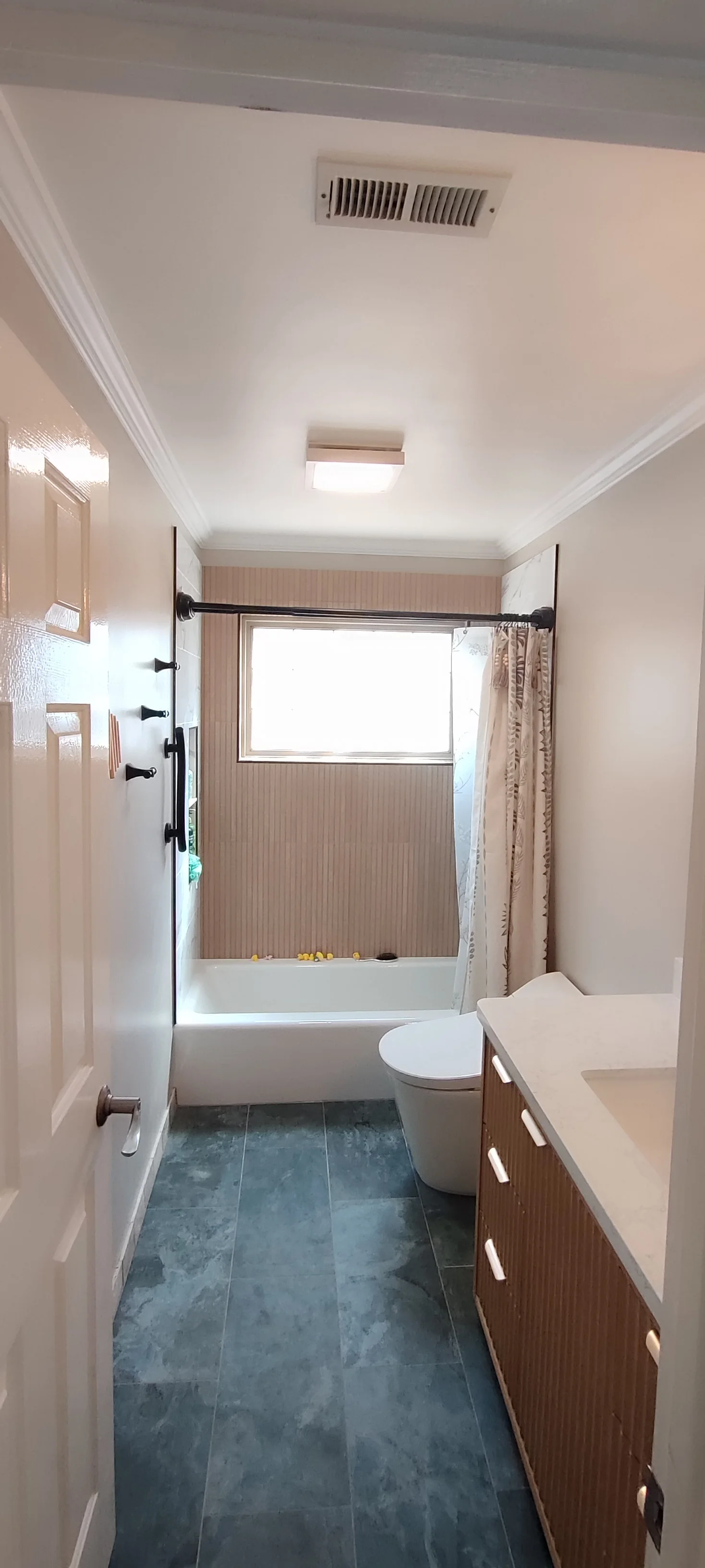 A wider doorway view of the completed bathroom, including the vanity and tiled floor.