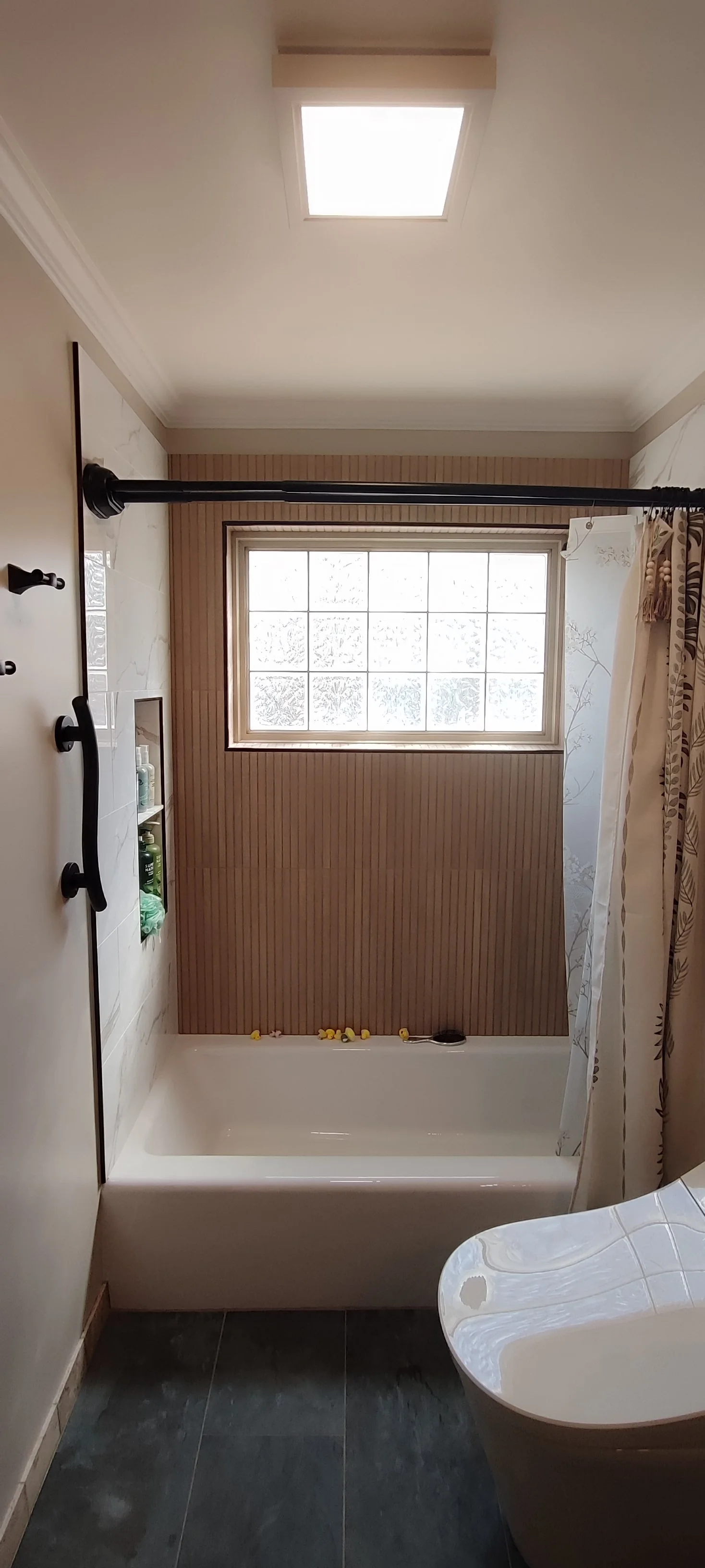 Front view of the bathtub, tiled back wall and glass-block window in the completed bathroom.