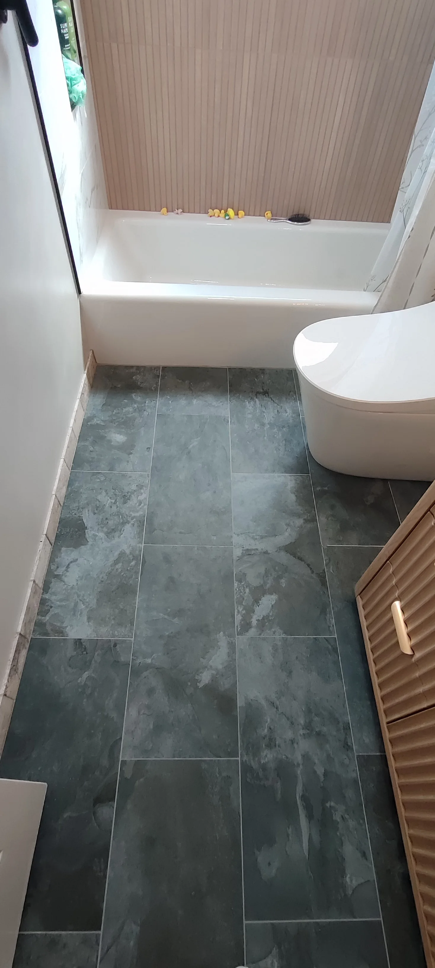 Dark floor tiles running from the doorway towards the bathtub.