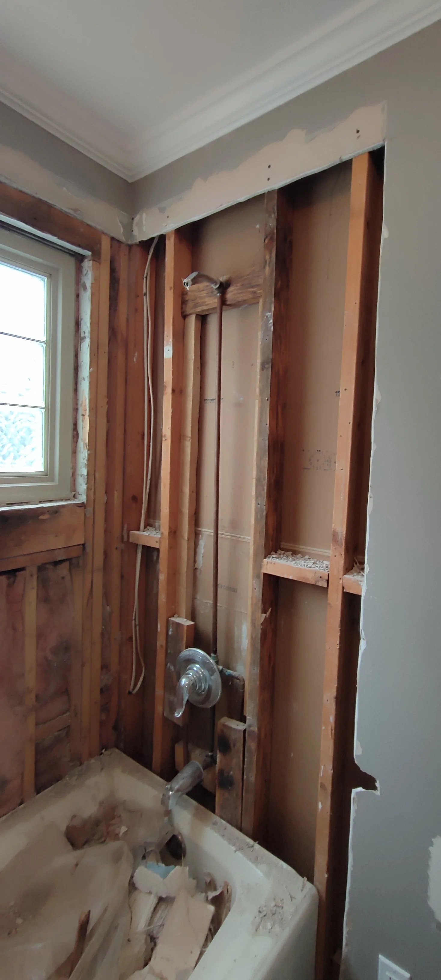 Exposed framing and pipework on the shower side during the renovation.