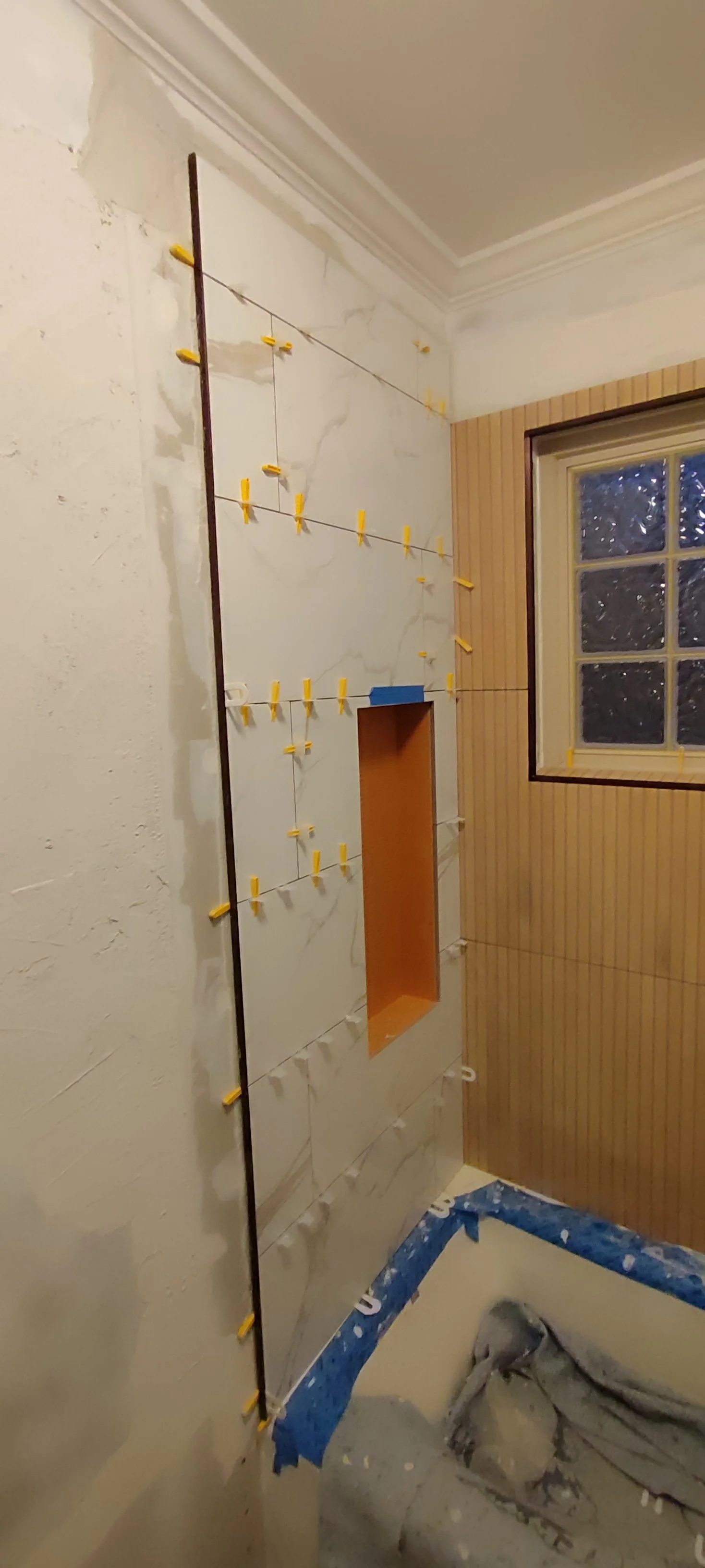 Left wall tiles being fitted around the niche, with tile clips still in place.