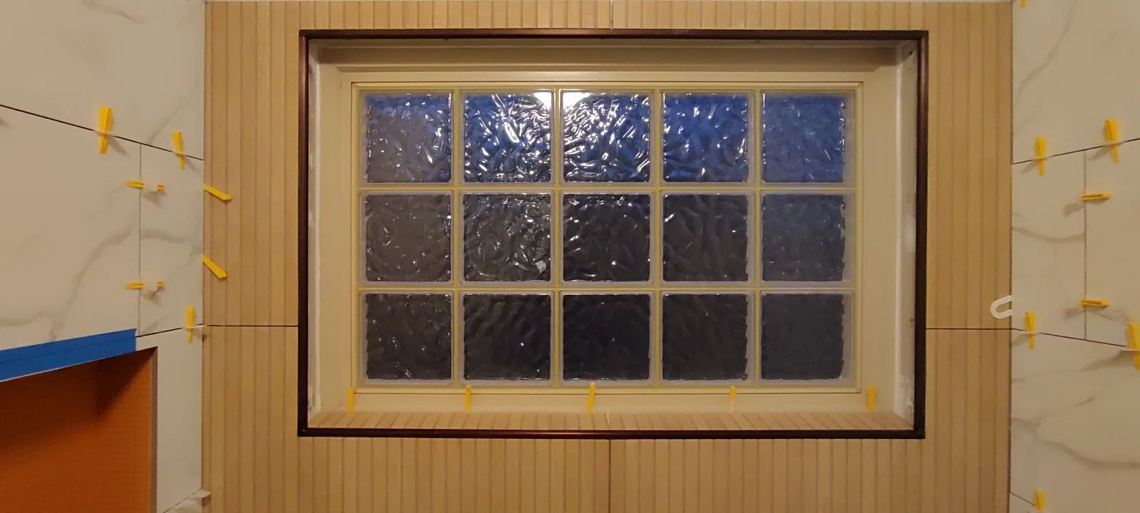 Tiling around the glass-block window during installation, with clips still in place.