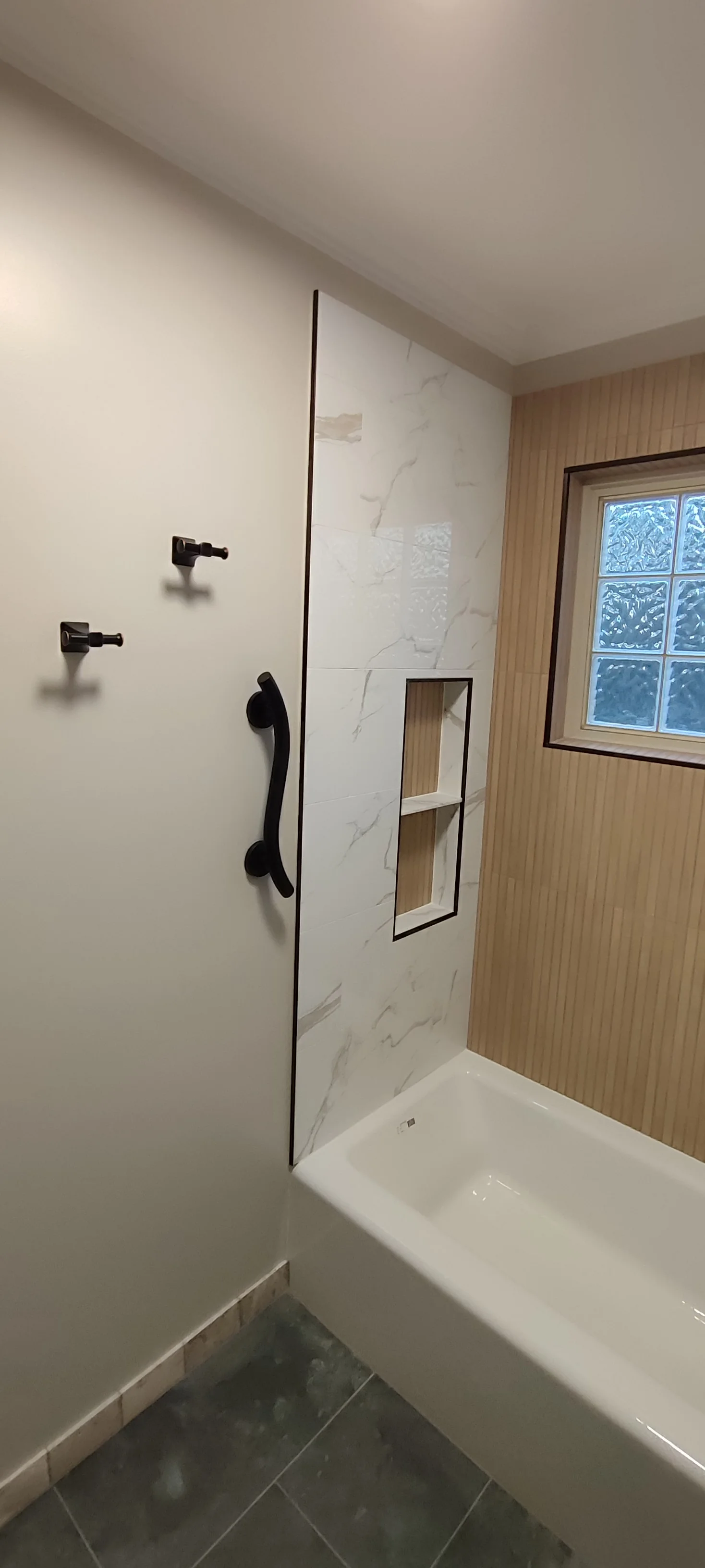 Left wall after tiling, showing the niche and black accessories before the final bathroom fit-out.