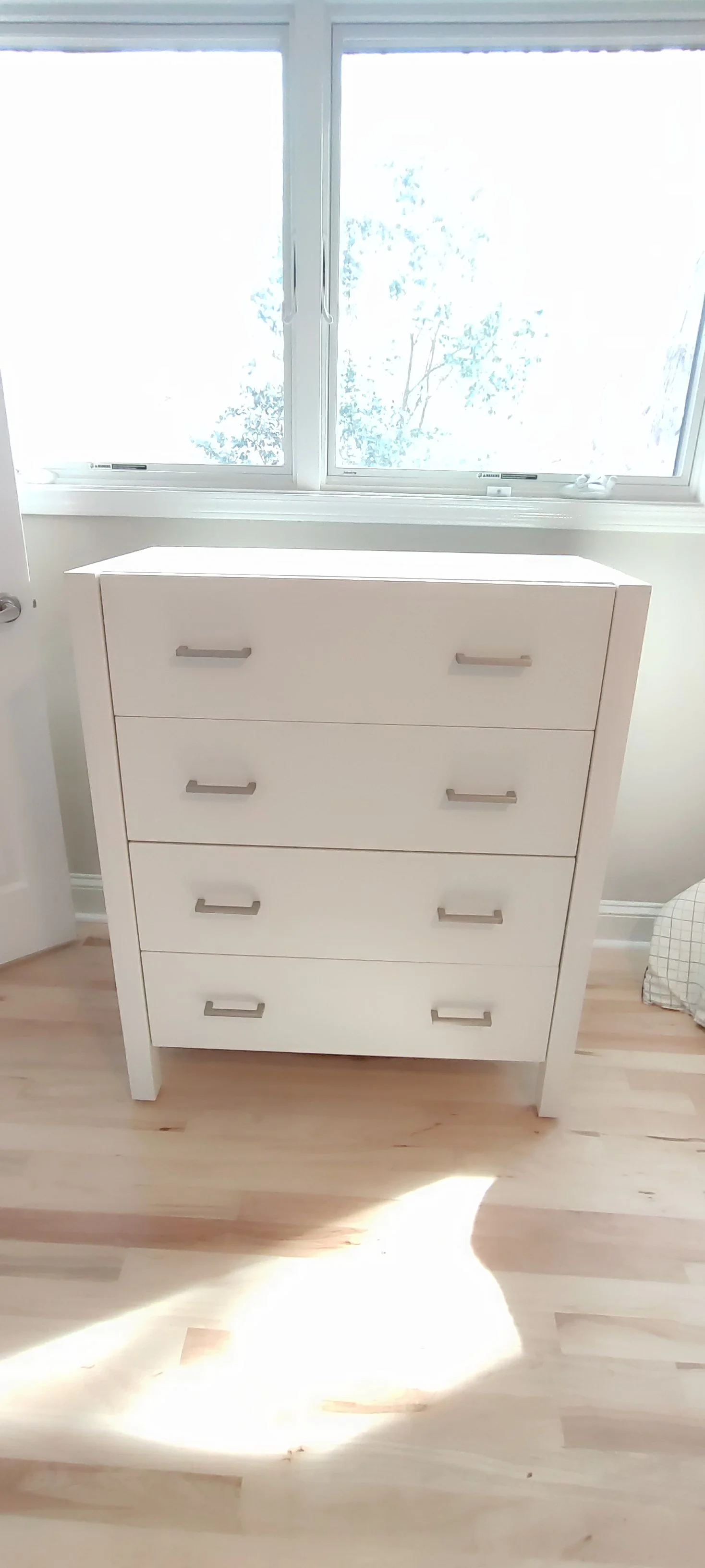 Front view of the finished white chest beneath a window