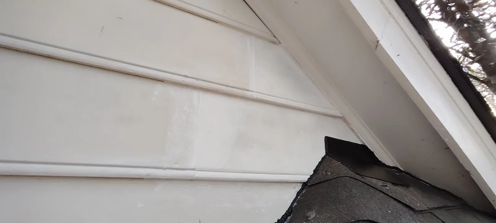 Metal flashing and sealed roof junction protecting the repaired exterior siding