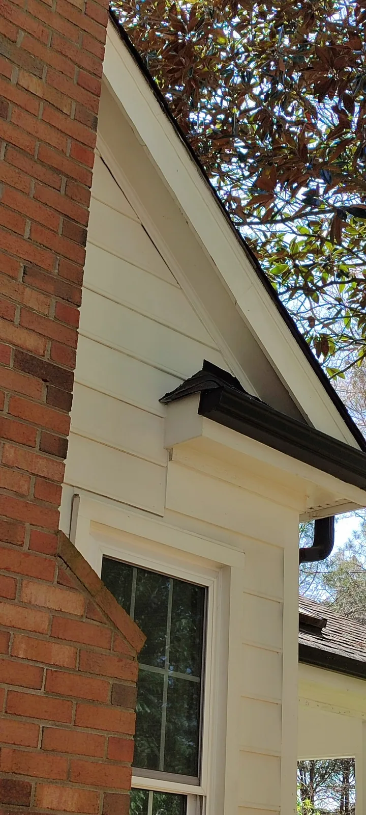 Final view of the repaired exterior siding and roof junction after painting and sealing