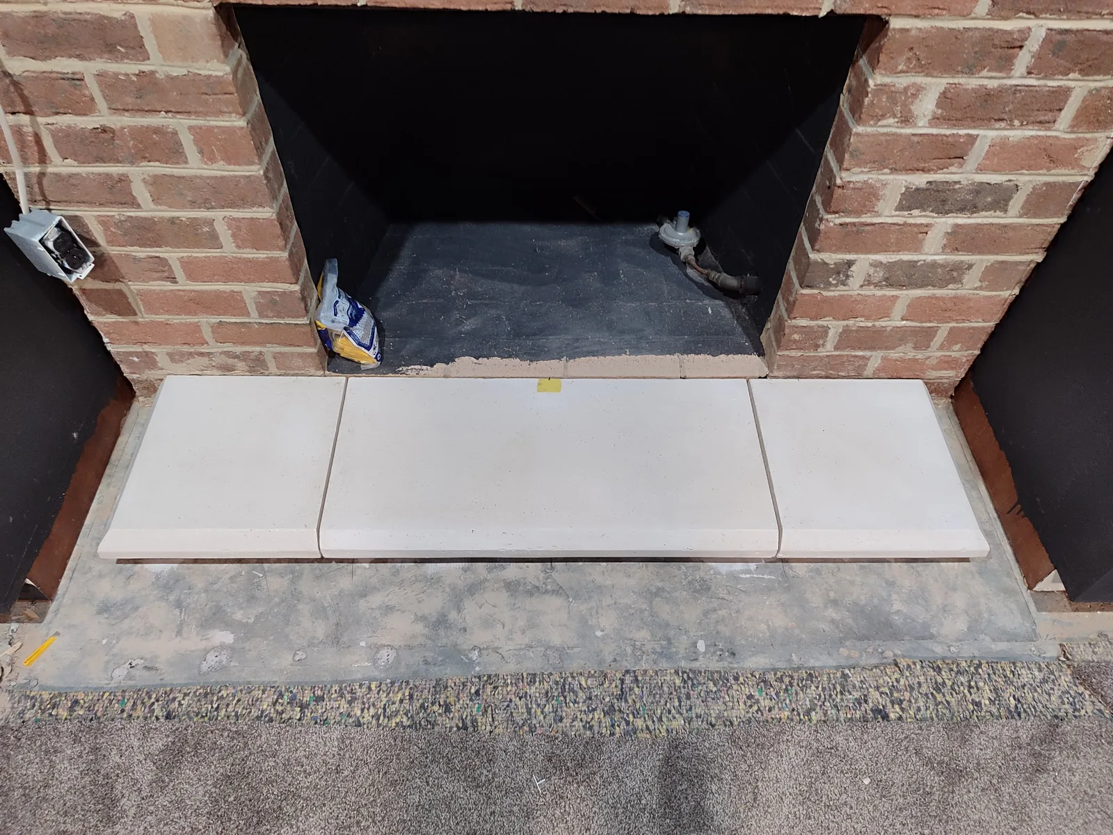 Lower fireplace area with mantel base components prepared for installation.