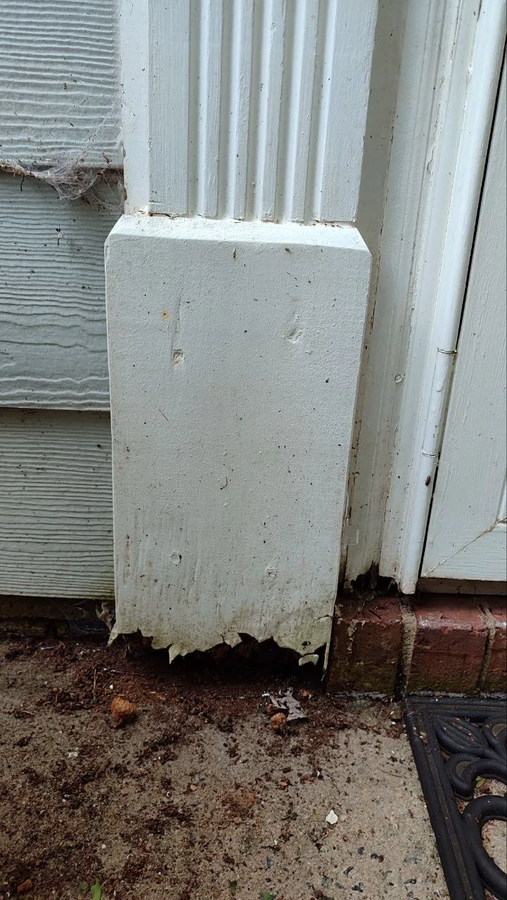 Damaged lower decorative trim beside the front door.