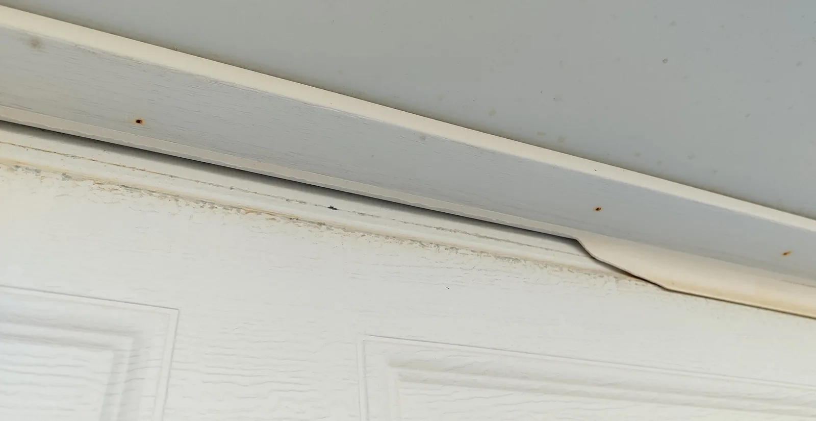 Damaged old weather seal near the upper section of the garage door opening.