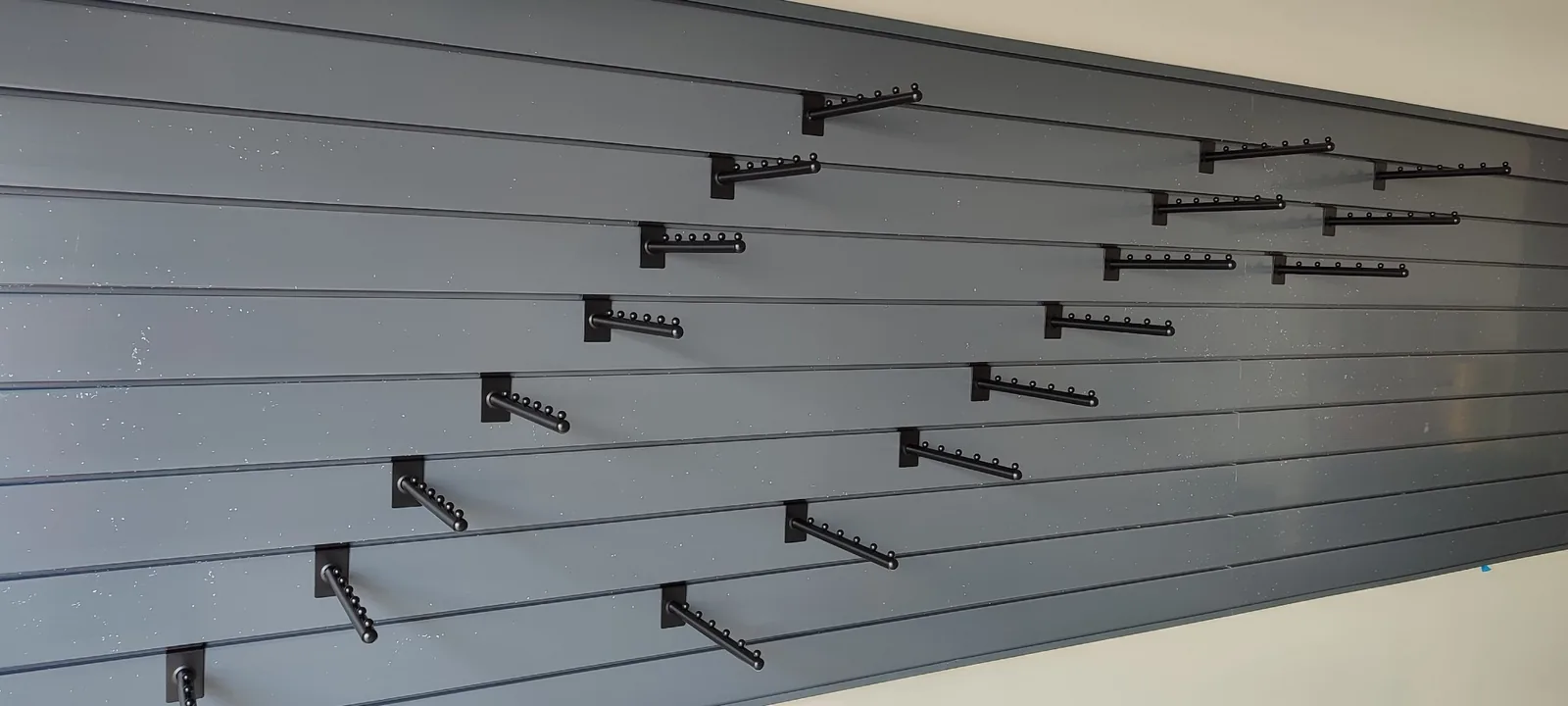 Close view of adjustable black hooks mounted in the garage slatwall panels