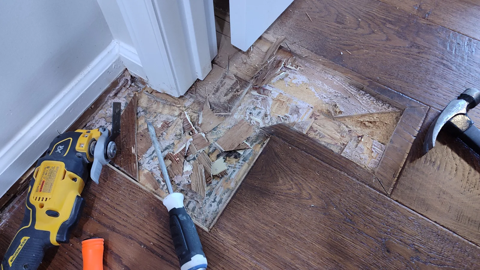 Opened hardwood floor section at a doorway during repair.