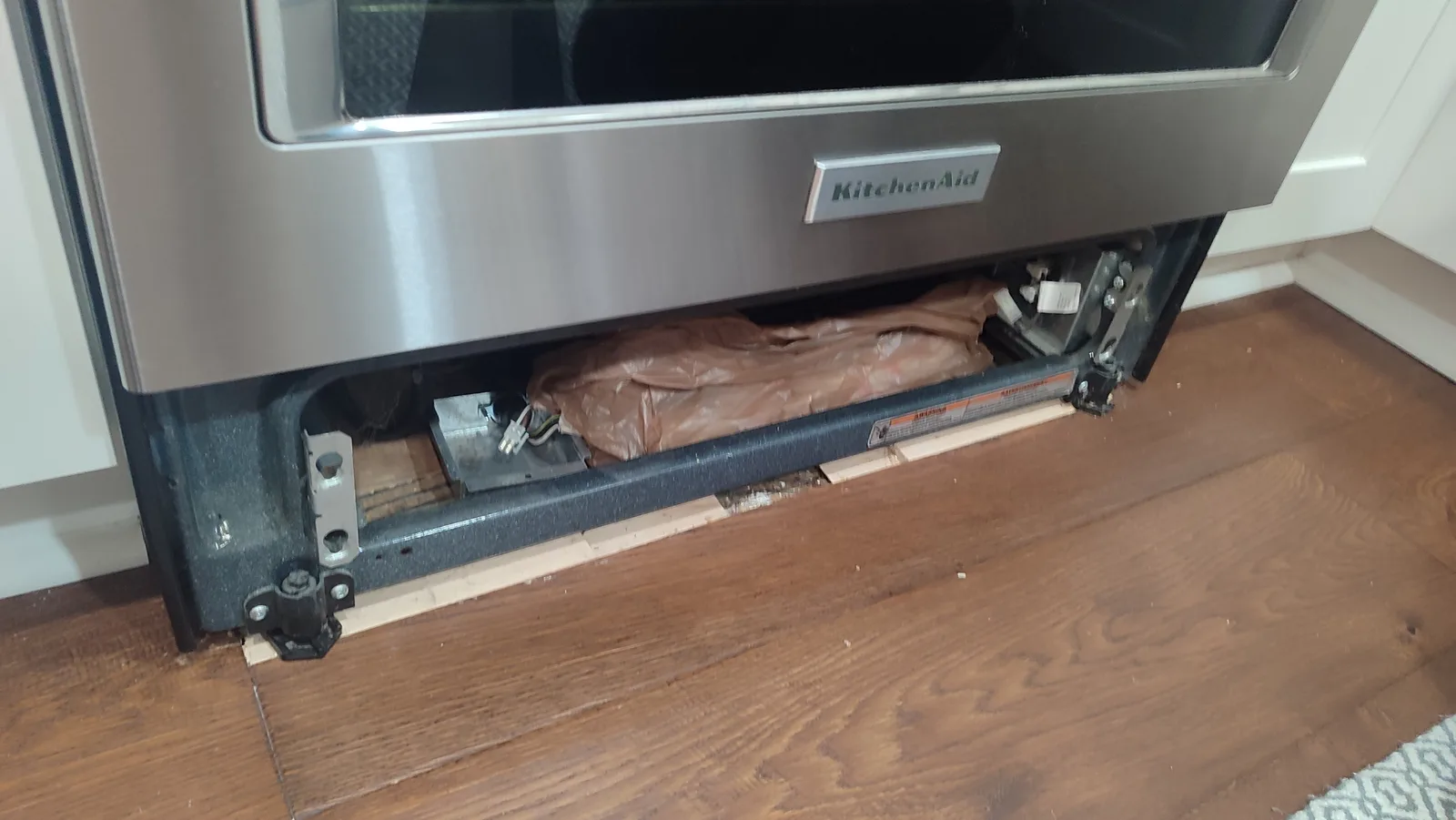 Hardwood floor area beneath a pulled-out electric stove before repair.
