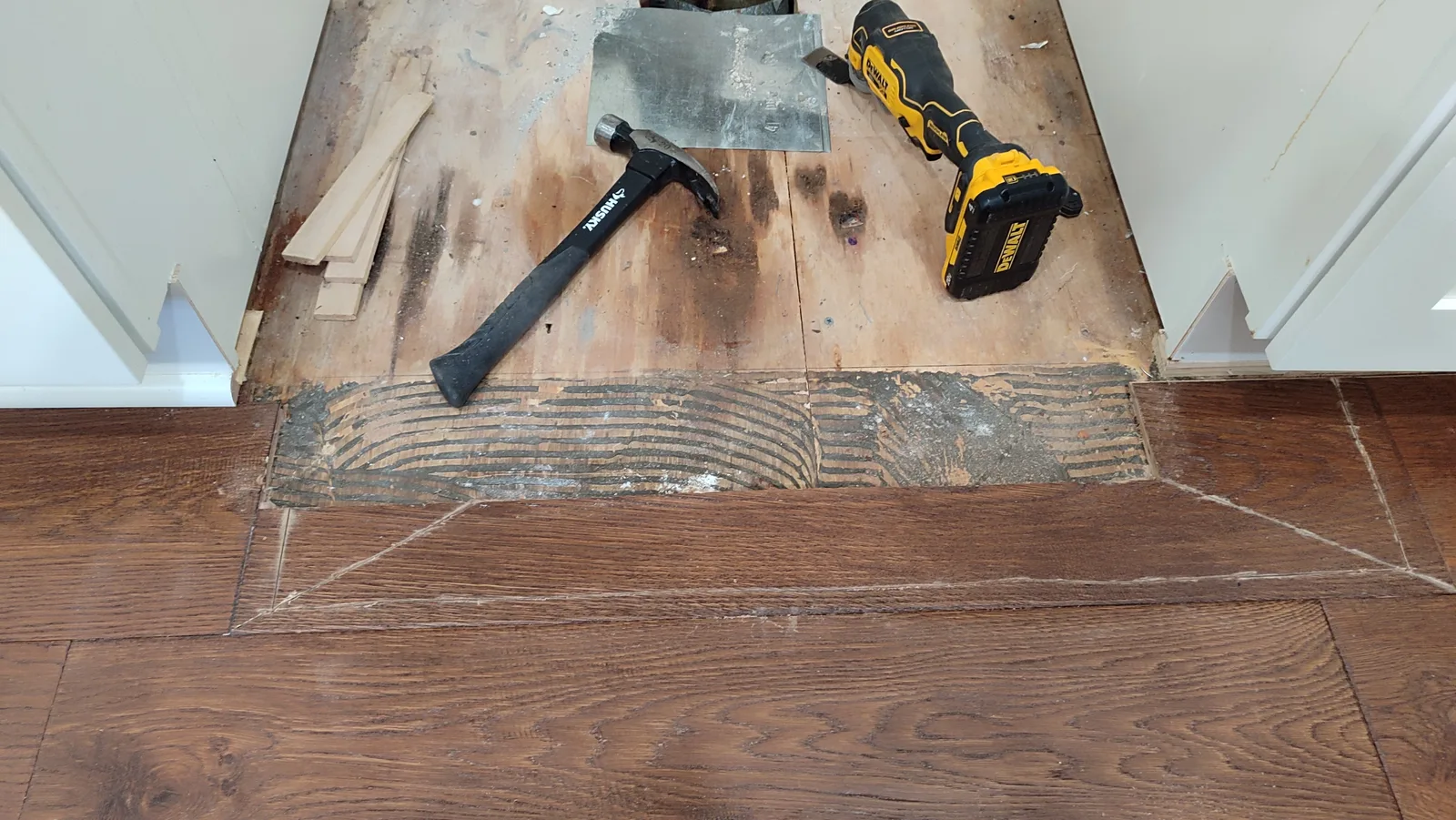 Opened hardwood floor section between kitchen cabinets during repair.