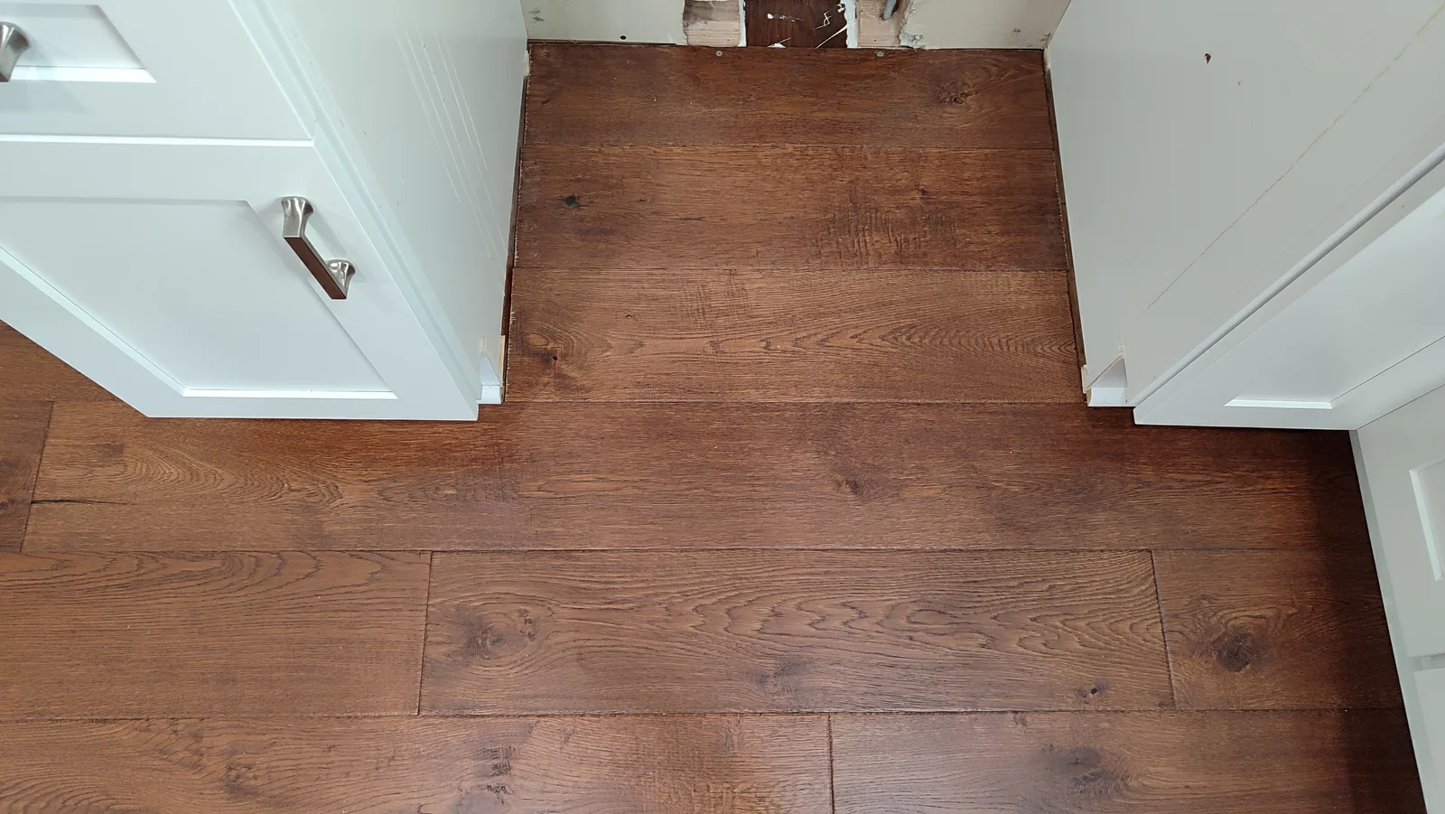 Restored hardwood floor beneath the electric stove after repair.
