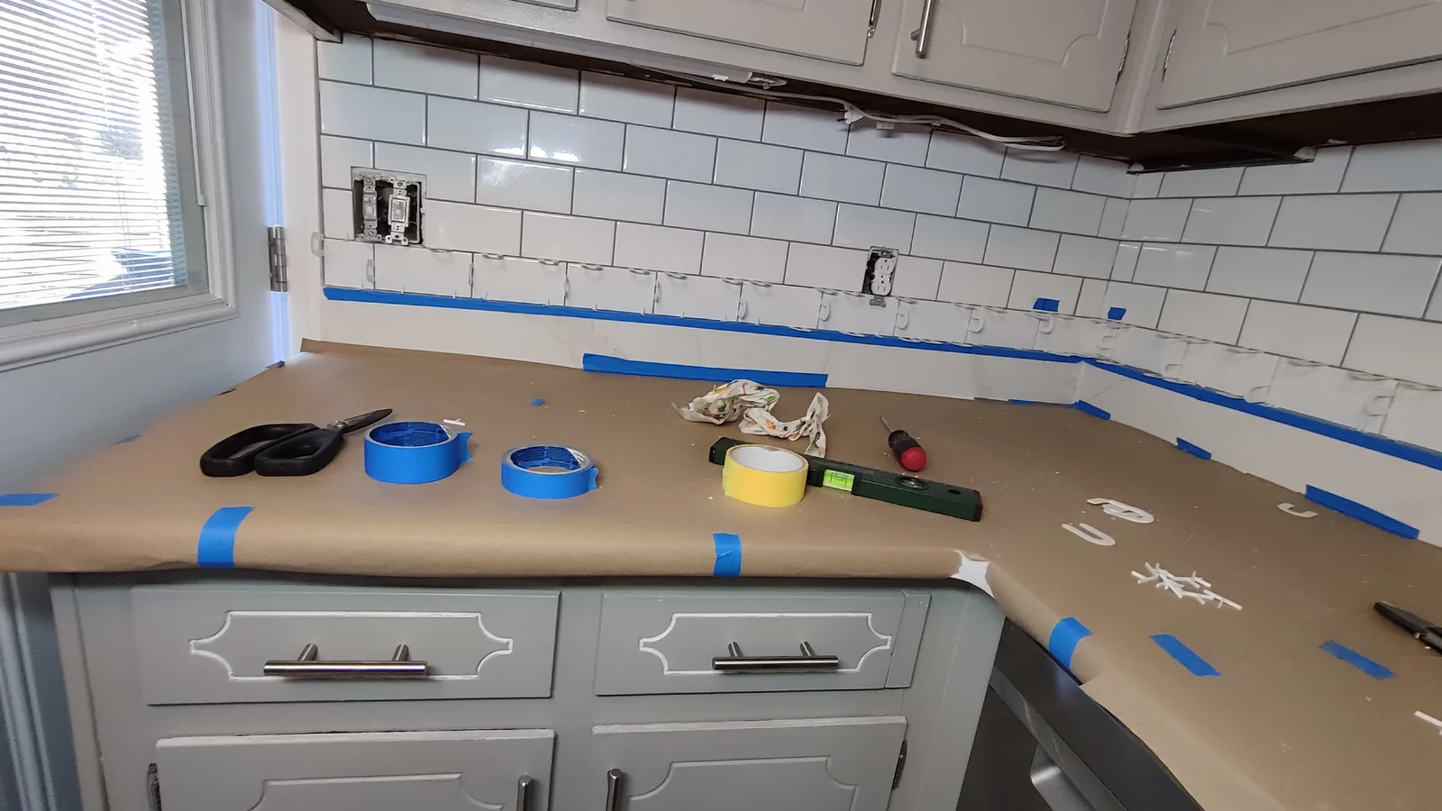 Installed lower tile row above the left counter during backsplash repair