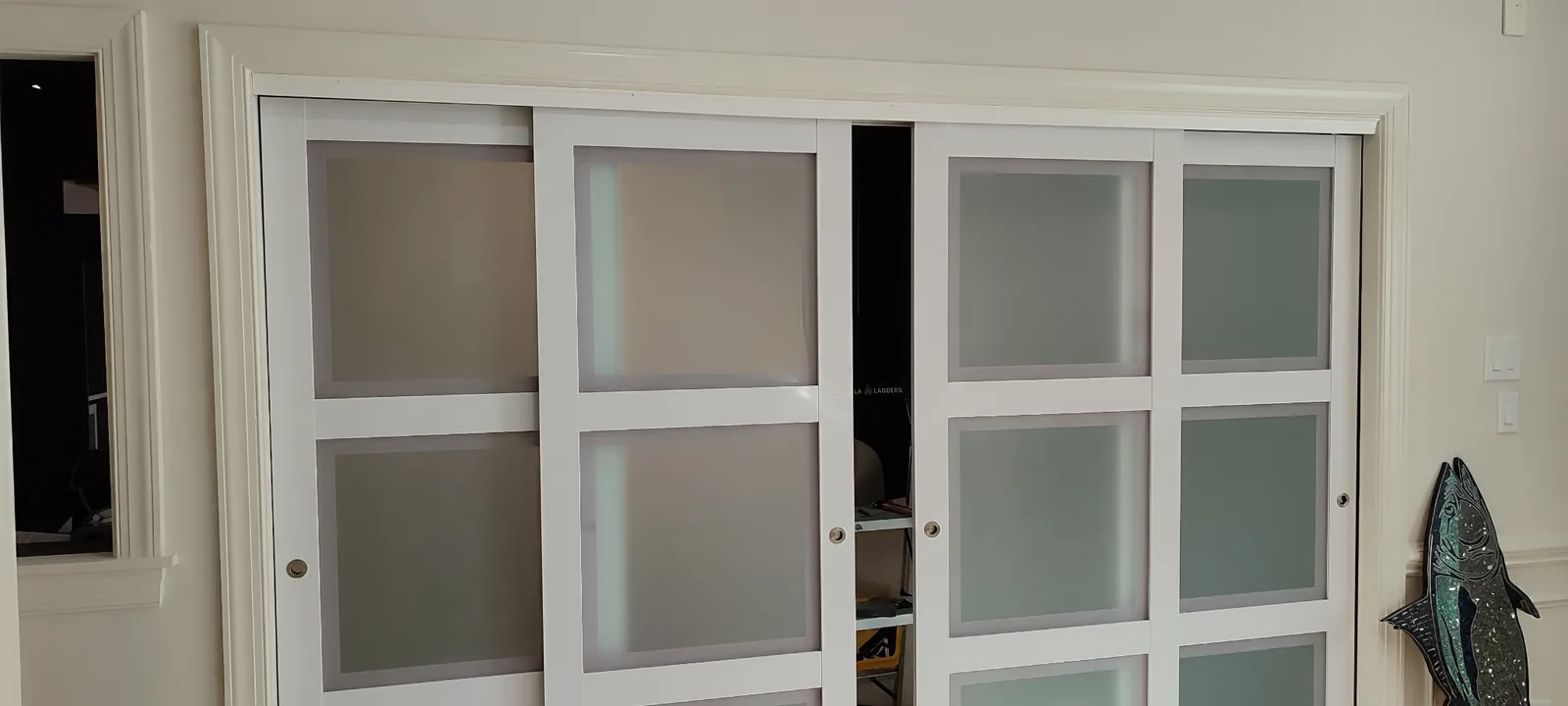 Four-panel frosted glass sliding door system installed in a wide interior opening