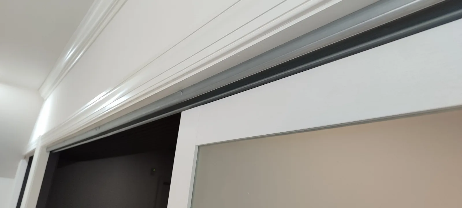 Close view of the top-hung sliding door track concealed behind custom trim