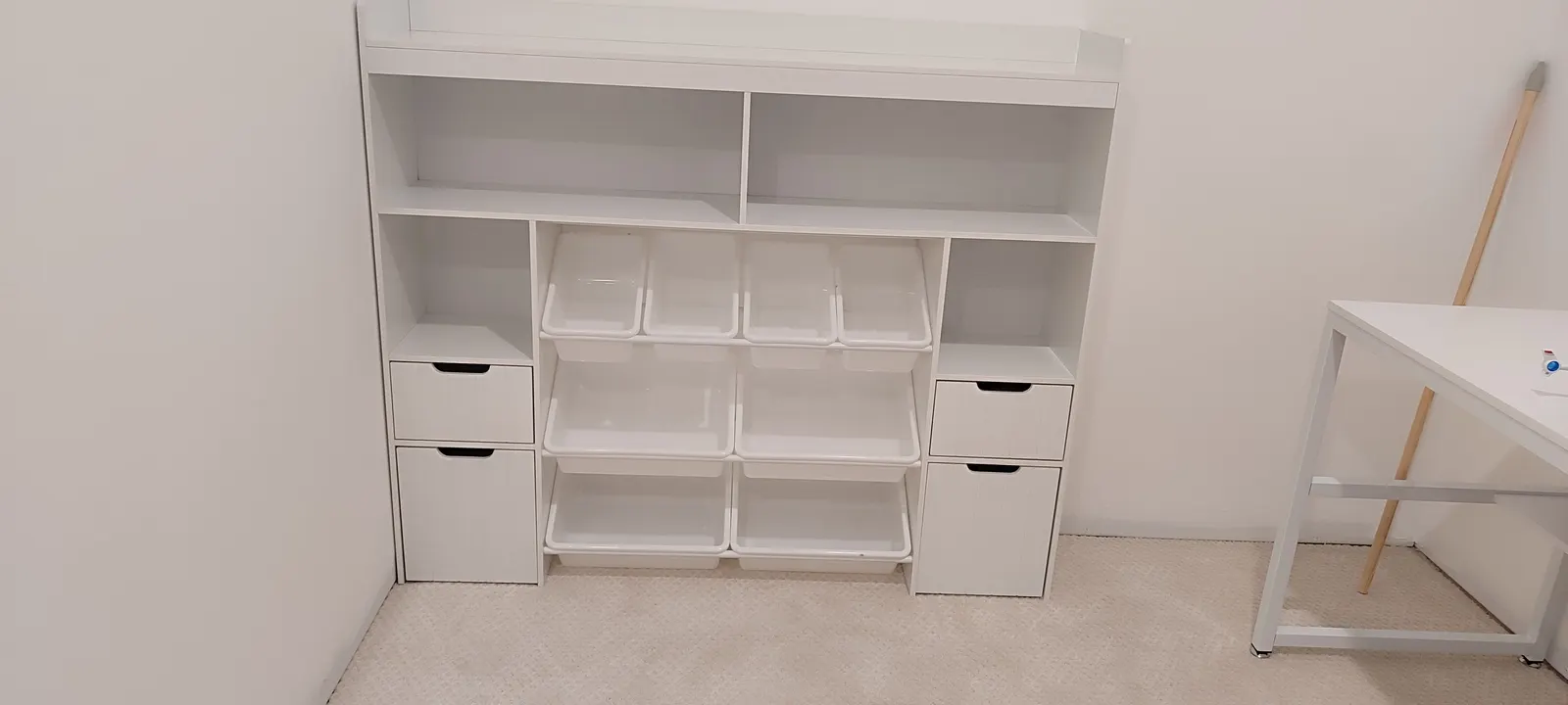 Assembled white playroom storage unit with shelves and bins