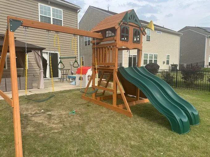 Assembled wooden playset with double slide and swings.
