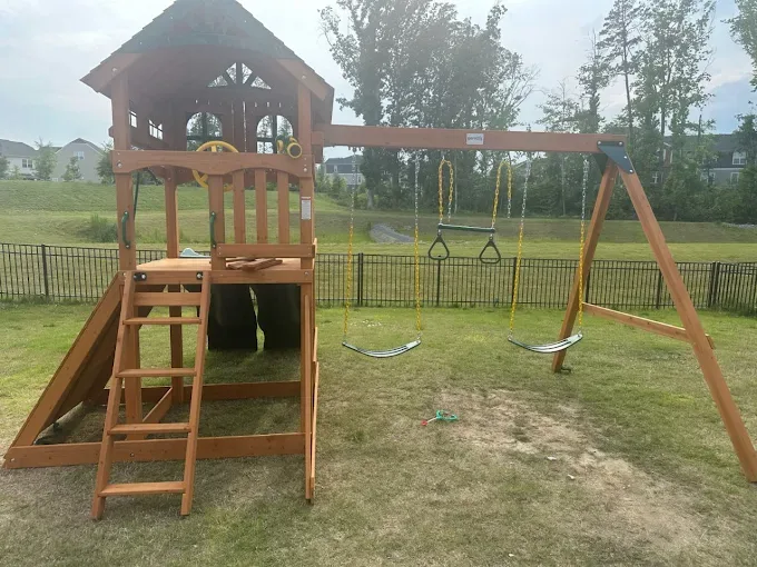 Completed wooden playset with ladder, play tower and swings.