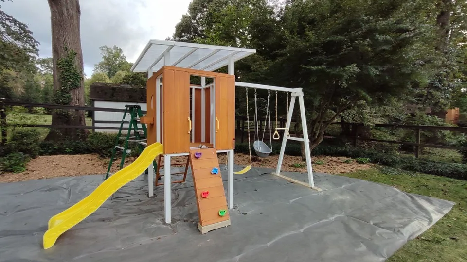 Assembled children's playset with clubhouse, slide and swings.