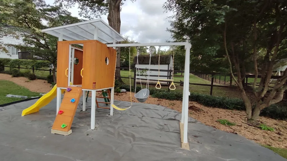 Completed playset with slide, climbing wall and swing frame.