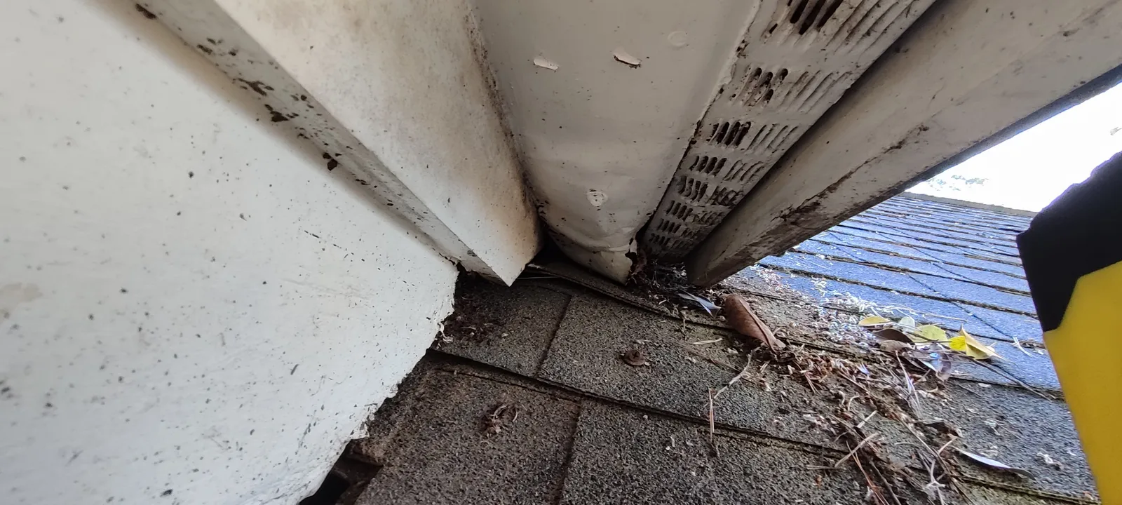 Damaged soffit area near the roof junction before restoration.