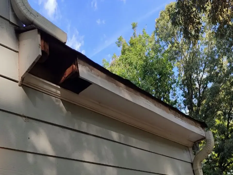 Exposed damaged soffit and fascia area before restoration.