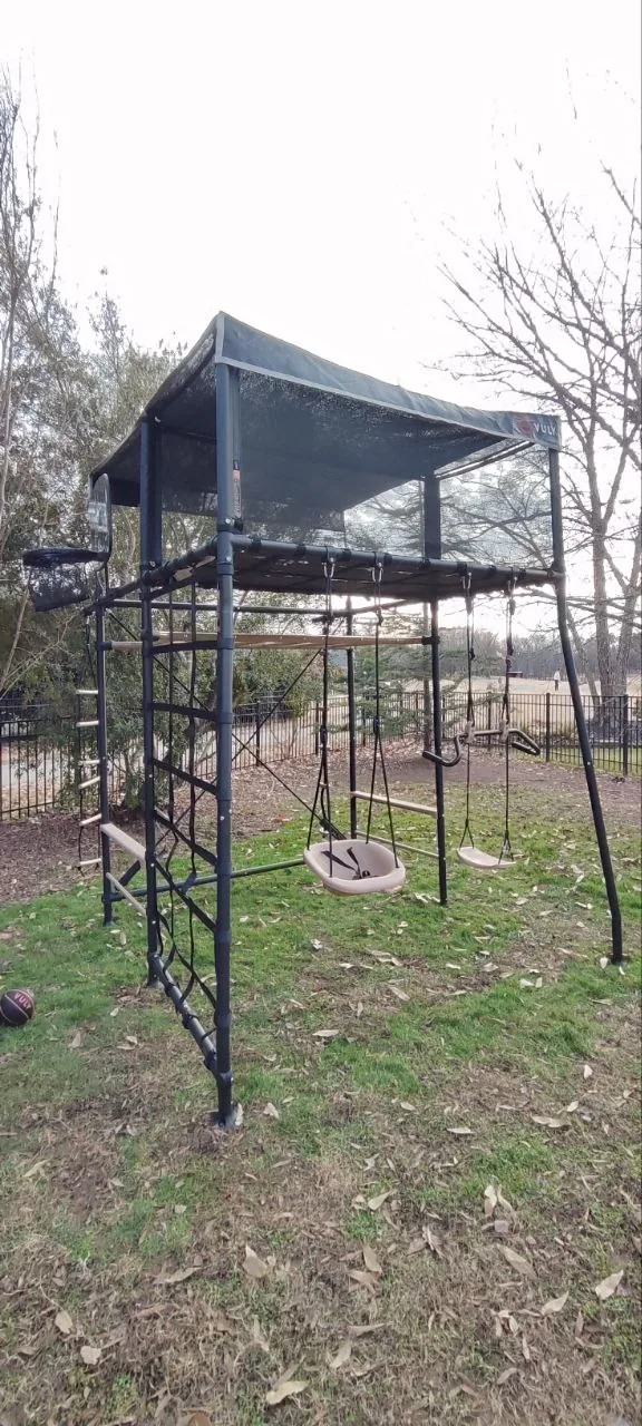 Completed Vuly Quest playset with swings, elevated cubby, and modular steel frame