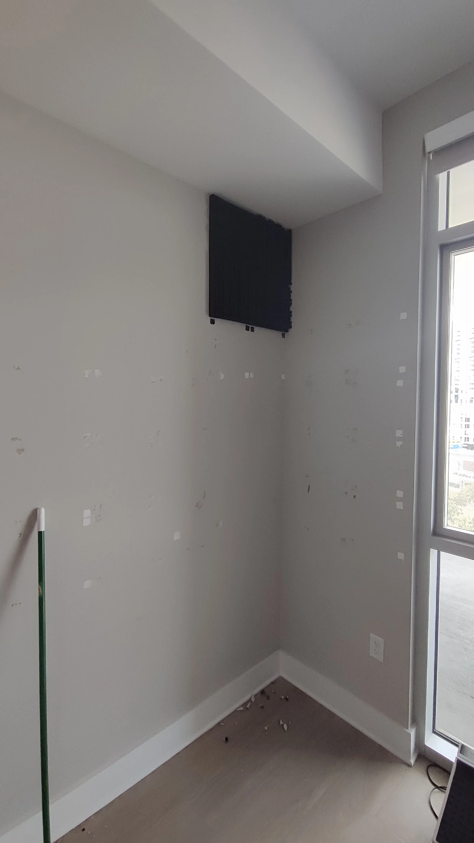 Acoustic panel and damaged wall at the corner with the window on the right