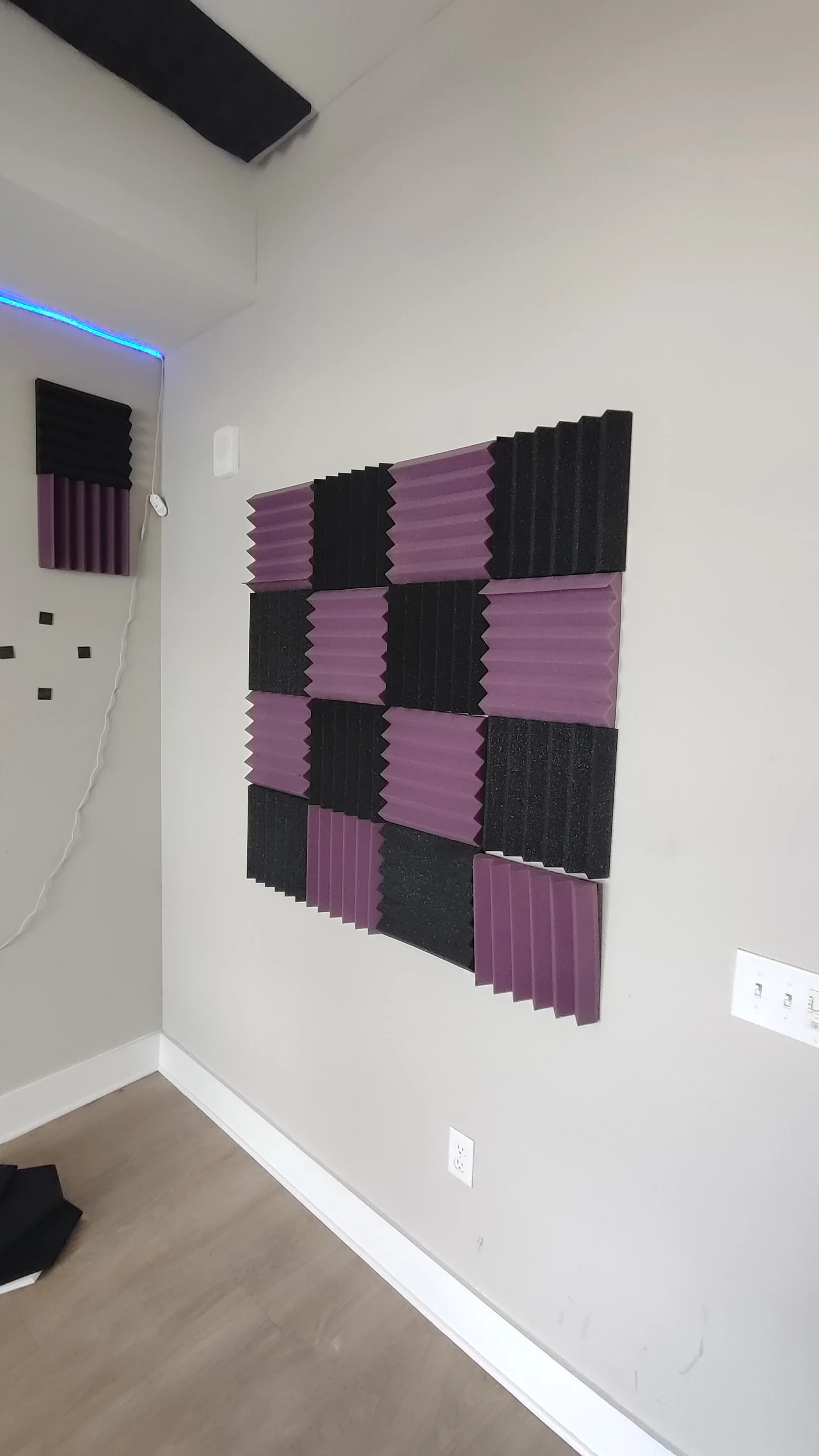 Purple and black acoustic panels on the wall beside the entry